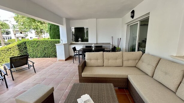 A covered outdoor seating area with a sofa, chairs, and a small table. - Groundfloor apartment next to the pool - ER702LT (La Torre Golf Resort)