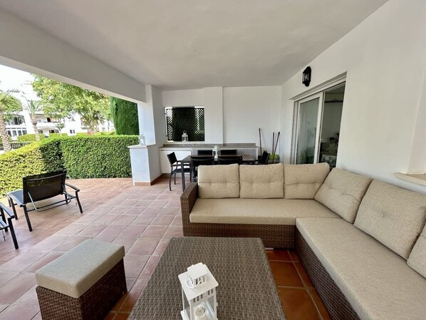 A covered outdoor seating area with a sofa, chairs, and a small table.