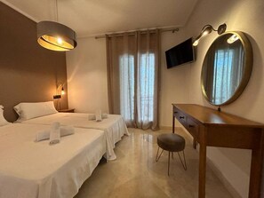 Une chambre d’hôtel avec deux lits, un bureau, une chaise, un miroir et une télévision.