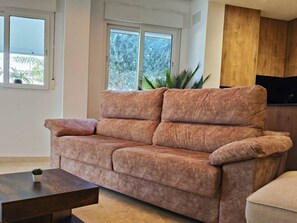 Un salon avec un canapé, une table basse et un téléviseur.