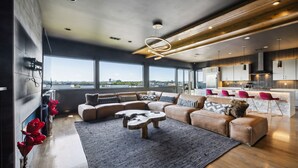 A modern living room with a sectional sofa, a coffee table, and a view of the city.