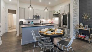 A modern kitchen with white cabinetry, a central island, and pendant lighting.