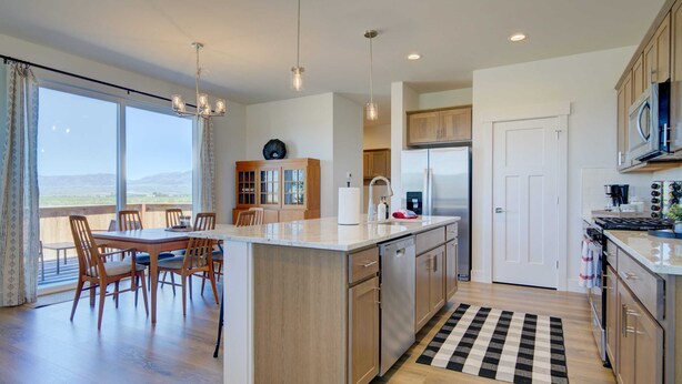 Una cocina moderna con una isla central, armarios de madera, electrodomésticos de acero inoxidable y un comedor con vistas.