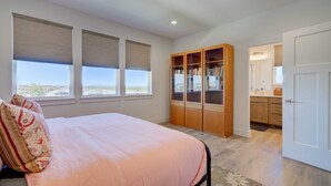 Un dormitorio con cama, un ventanal grande, una estantería empotrada y vistas al exterior.