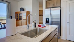 Una cocina moderna con un lavamanos de acero inoxidable, armarios de madera y un refrigerador empotrado.