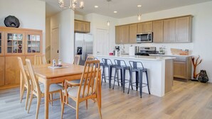 Una cocina moderna con armarios de madera, una isla central con taburetes y un comedor con sillas de madera.
