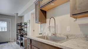 Una cocina moderna con un lavamanos doble, armarios de madera y encimera de mármol.
