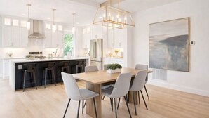 A modern kitchen with a central island, bar stools, and a dining table with chairs. - Spacious Montana home near Big Sky and BZN airport (Belgrade)