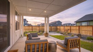 A covered patio with outdoor furniture, a wooden fence, and a view of neighboring houses. - Spacious Montana home near Big Sky and BZN airport (Belgrade)