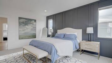 A bedroom with a bed, bedside table, bench, and a large window.