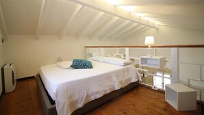 Quarto com cama, mesas de cabeceira, luminária e aquecedor.