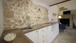 Cozinha com parede de pedra, pia e bancada de madeira.