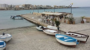 Una zona frente al agua con varias embarcaciones pequeñas amarradas cerca de un edificio con terraza.