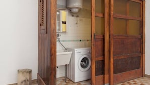 Un baño pequeño con lavadora, lavabo y puerta de madera.