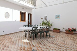 A room with a white table and chairs, a potted plant, and a patterned floor. - VILLETTA AL MARE OTRANTO (OTRANTO)