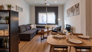 A modern living room with a sofa, a dining table set for two, and a television. - Nice apartment in Vila de Gracia (Barcelona)