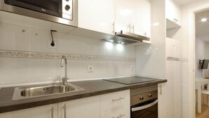 Una cocina moderna con armarios blancos, un lavamanos de acero inoxidable, un microondas y un horno.