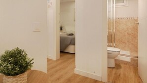 Un baño con inodoro, ducha y un pequeño espejo en la pared.