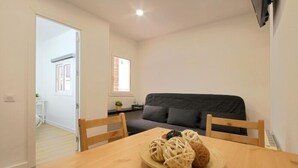 A compact living space with a dining table, a sofa, and a small kitchen area. - Functional apartment near Barcelona (L'Hospitalet de Llobregat)