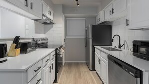 A modern kitchen with white cabinetry, stainless steel appliances, and a wooden countertop. - The Landry 157 | Spacious and Cozy 1 Bedroom 1bth (Arlington)