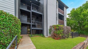 Un immeuble d’appartements moderne, doté d’une pelouse bien entretenue, d’une clôture en bois et d’un portail en métal.