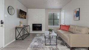 Ein Wohnzimmer mit Kamin, einer Couch, einem Couchtisch und einem an der Wand befestigten Fernseher.