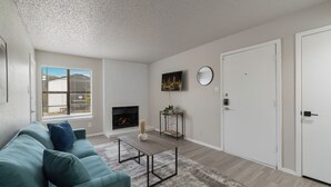 Un salon avec un canapé, une table basse, une cheminée et une porte.