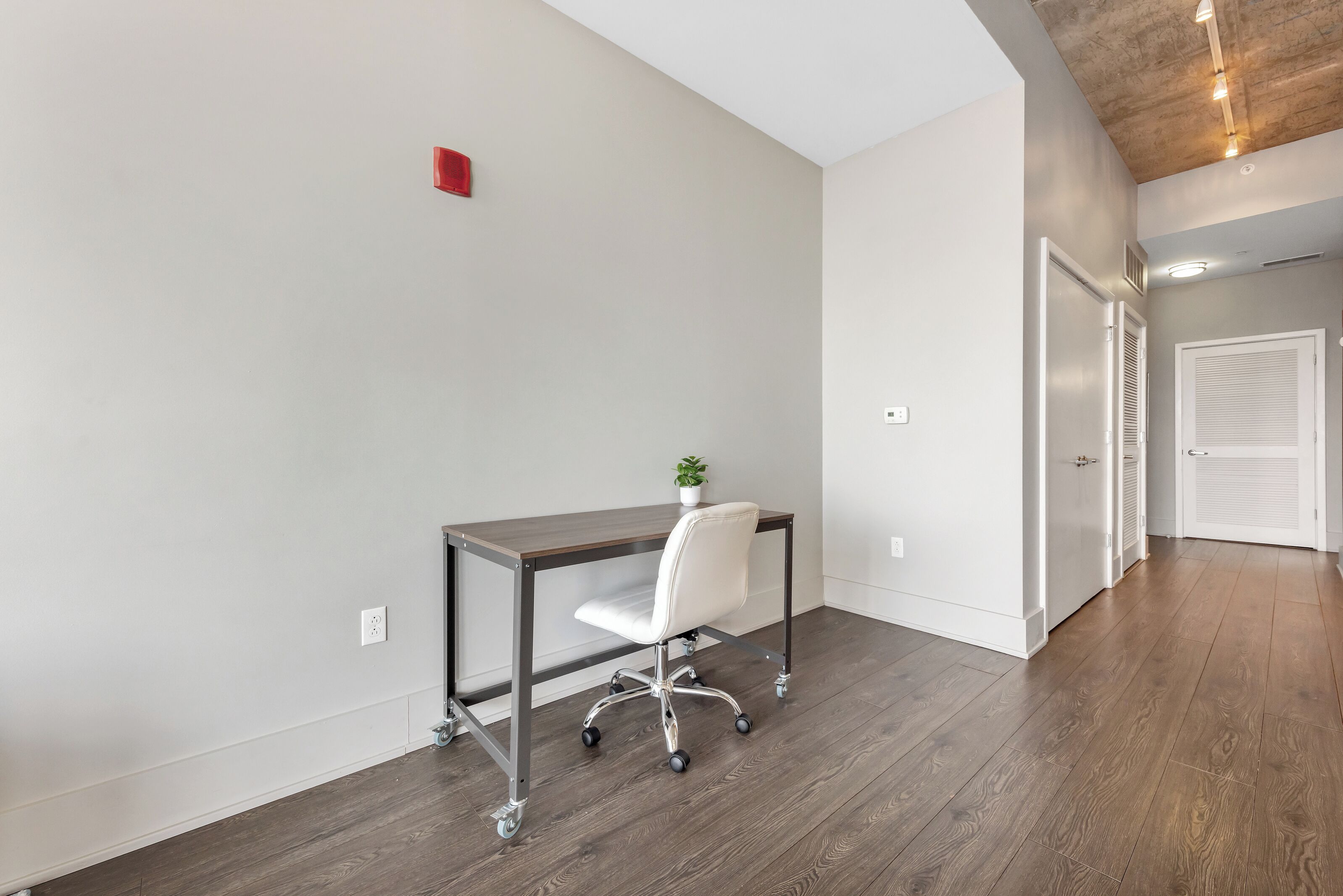 Un espace de bureau moderne comprenant un bureau, une chaise et une plante en pot.