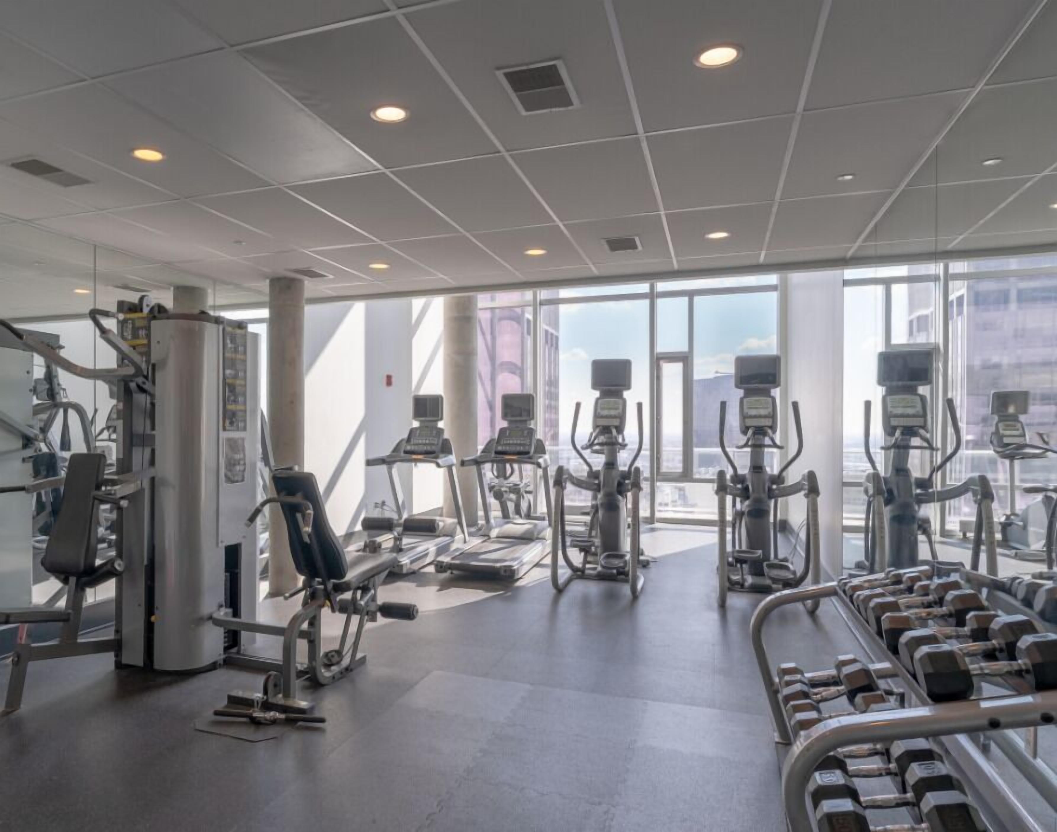 A gym with treadmills, weight machines, and dumbbells.