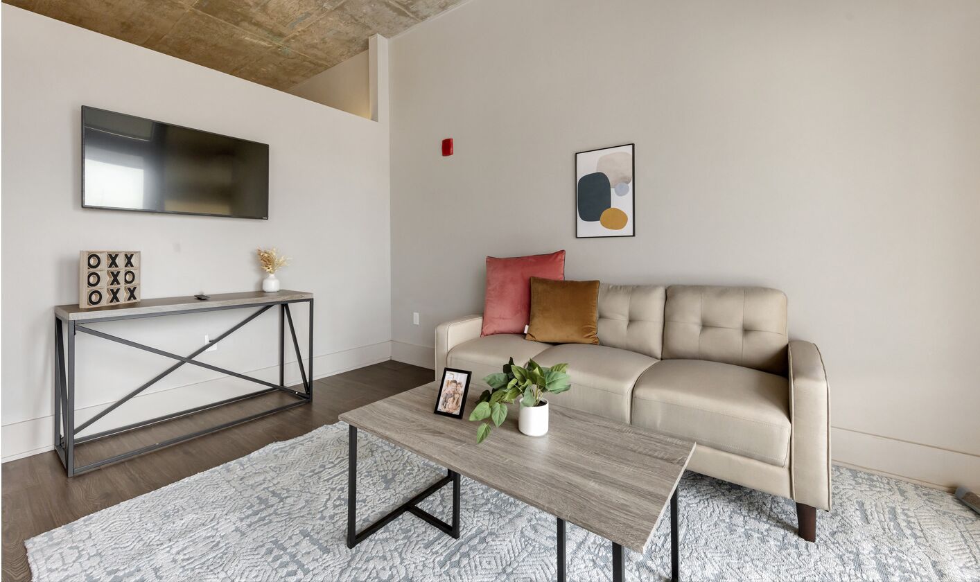 Una sala de estar con un sofá, una mesa de centro, un televisor y una consola decorativa.