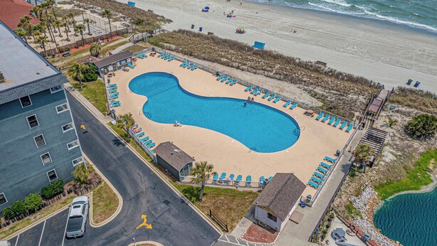 An aerial view of a beachside resort with a large swimming pool, beach chairs, and a view of the ocean. - Myrtle Beach Resort 6211 (Myrtle Beach)