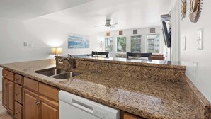 A kitchen with granite countertops, a dishwasher, and a dining area with chairs and a table. - Myrtle Beach Resort 6211 (Myrtle Beach)
