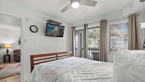A bedroom with a bed, a ceiling fan, a clock, a TV, and a window with curtains. - Myrtle Beach Resort 6211 (Myrtle Beach)