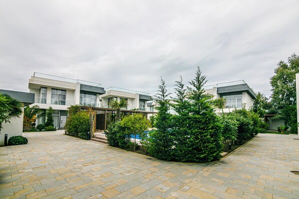 A courtyard with a paved walkway, surrounded by modern buildings and greenery.