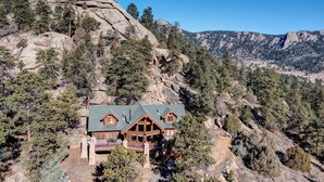 A lodge with a prominent rock formation in the background, surrounded by dense forest.