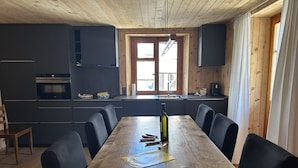 Een eetgedeelte met een houten tafel, zwarte stoelen en een fles wijn.