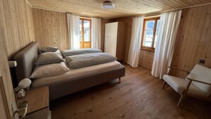 Een kamer met houten lambrisering, een bed, een stoel en een raam.