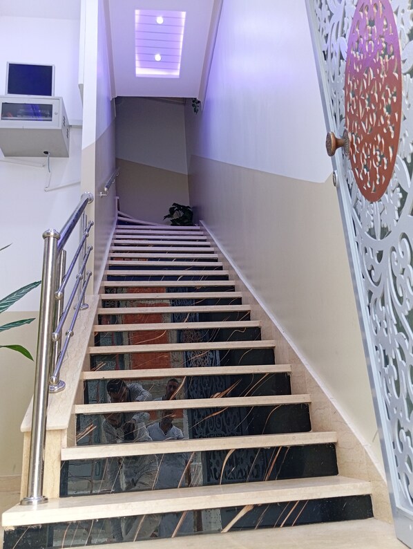 Un escalier avec des marches en marbre, des rampes en métal et des panneaux décoratifs sur les murs.