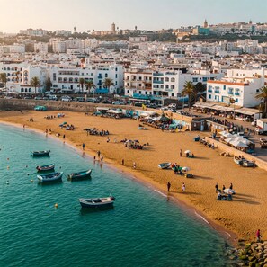 Un pueblo costero con playa de arena, varias embarcaciones y edificios con balcones.