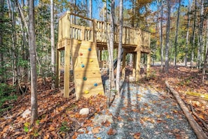 A wooden play structure in a forest. - Charming Treehouse Escape Among Nature's Blooms (Pittsboro)