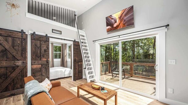 Een moderne woonkamer met een vide, een schuifpui naar een terras en een groot raam.