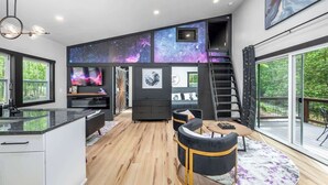 Een modern interieur met een keuken, een eethoek en een trap naar een balkon.