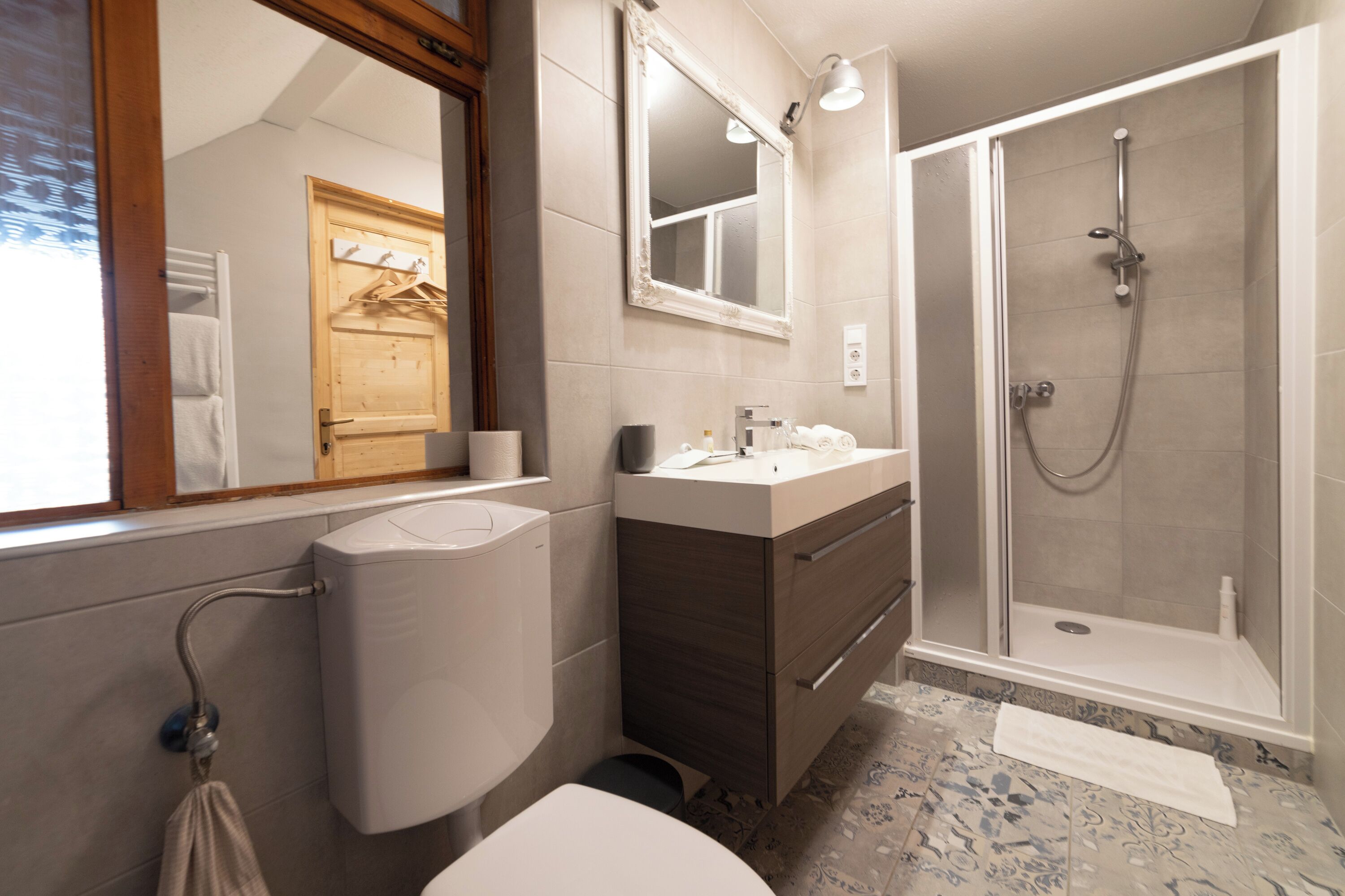 Une salle de bain moderne équipée de toilettes, d’un lavabo, d’un miroir et d’une douche.