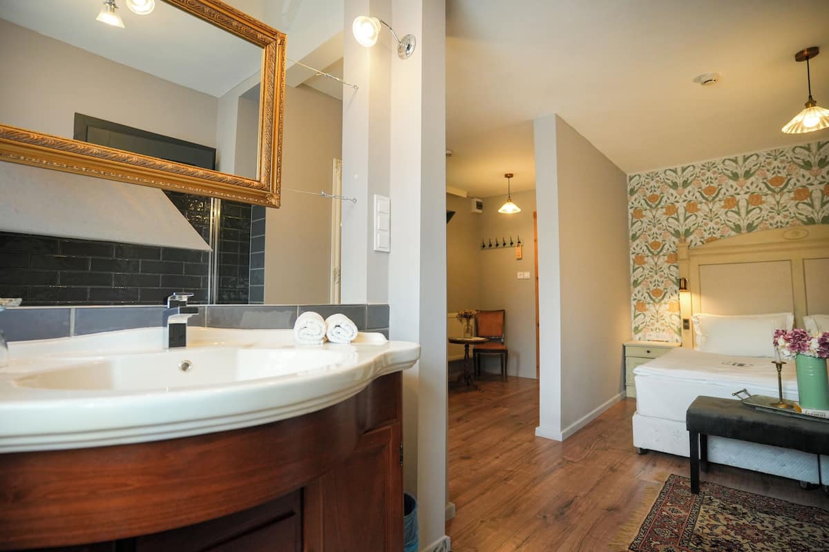 Un bany modern amb un mirall gran, un lavabo blanc i un armari de tocador de fusta.