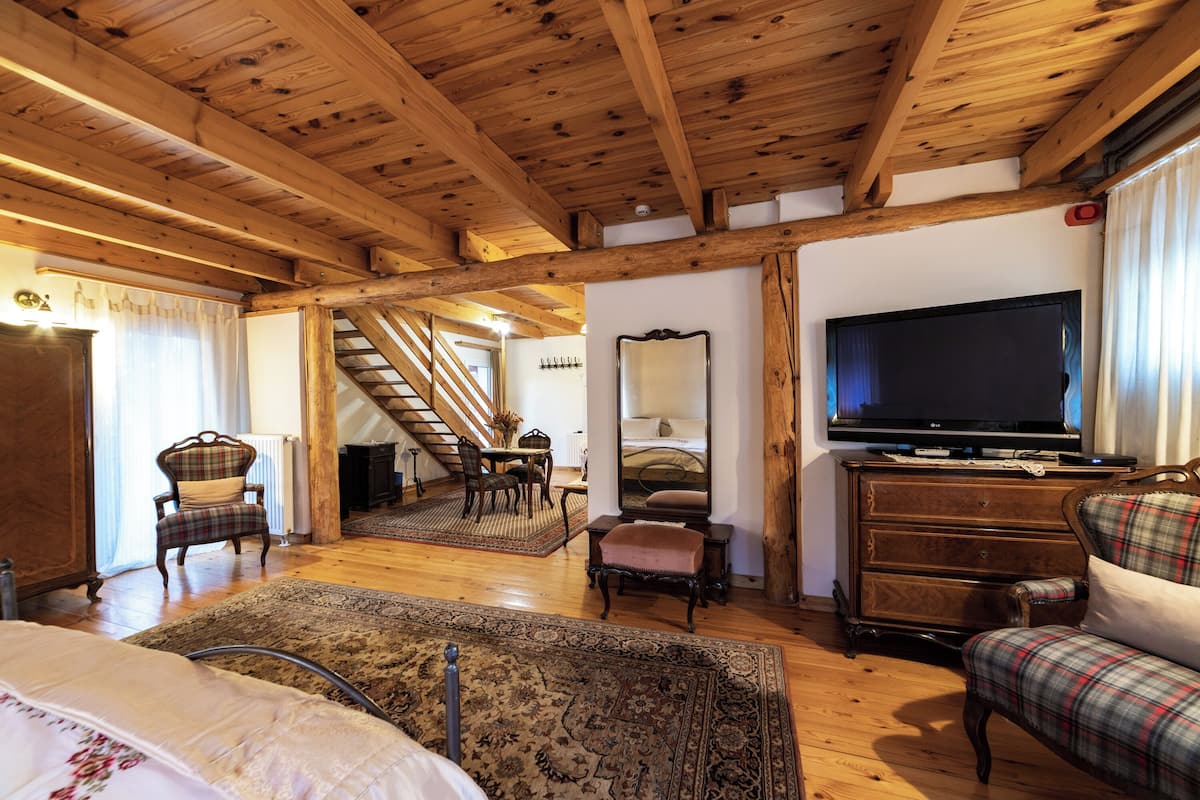Una habitació acollidora amb sostre de fusta, televisió, sofà i zona de menjador amb cadires i taula.