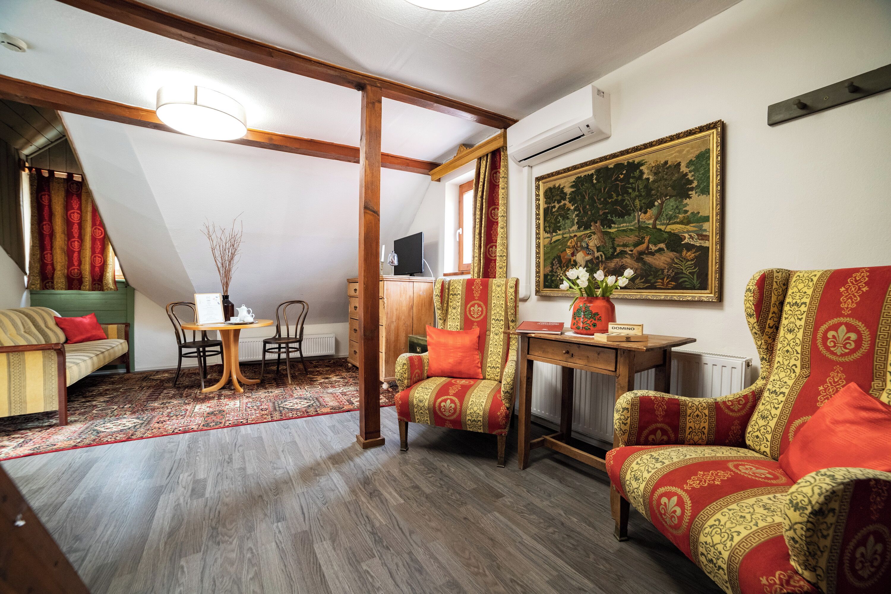 A cozy room with a dining table, two chairs, a sofa, and a chair with a patterned upholstery.