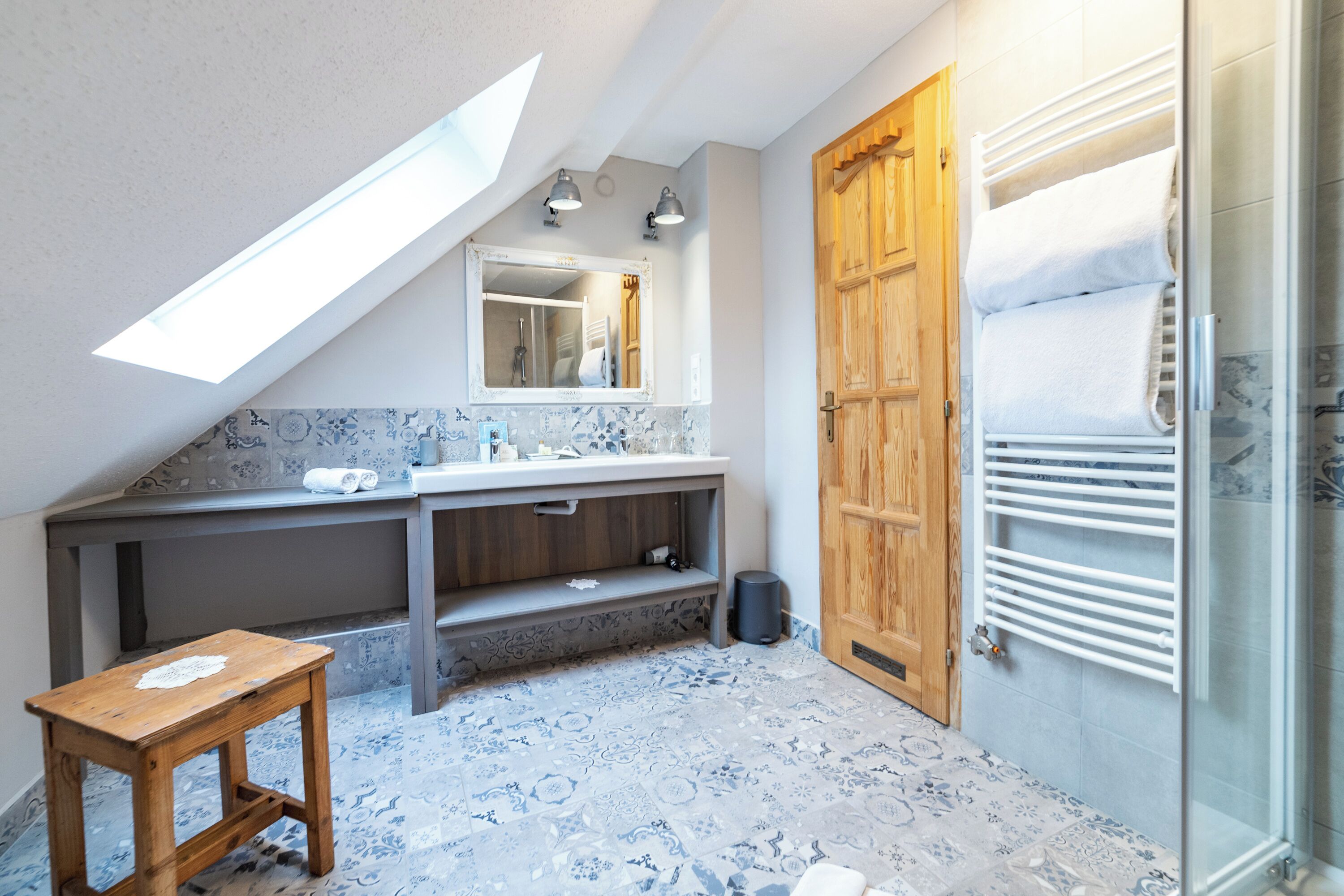 A bathroom with a skylight, wooden door, and a shower area.