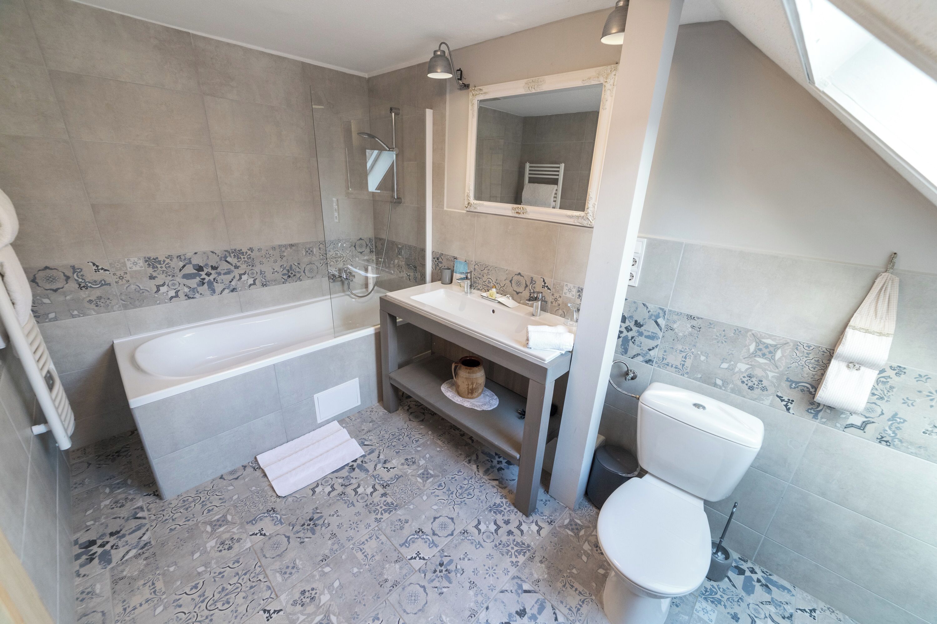 A bathroom with a bathtub, sink, toilet, and a mirror.