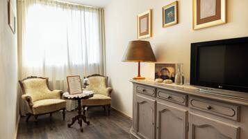A room with two armchairs, a small table, a television, and a cabinet.