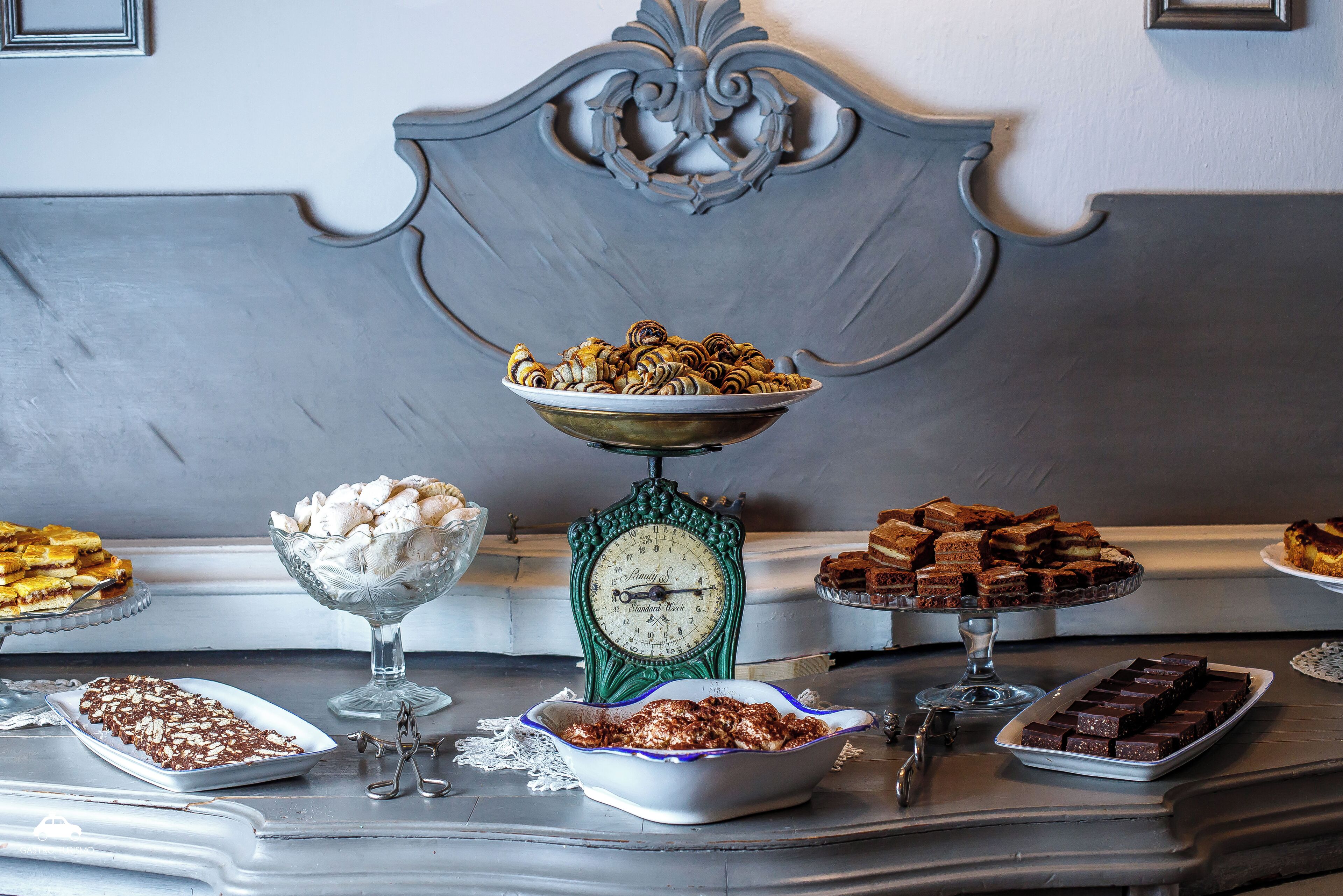 Una mesa de buffet con diversos postres y una balanza antigua.